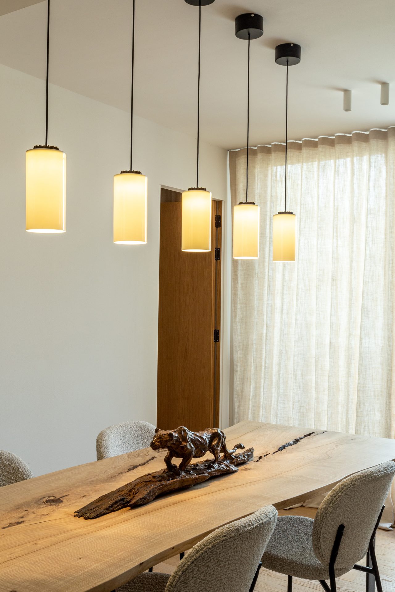 Solid wood dining table with bronze sculpture and pendant lights, Apartamento Perla, Barcelona
