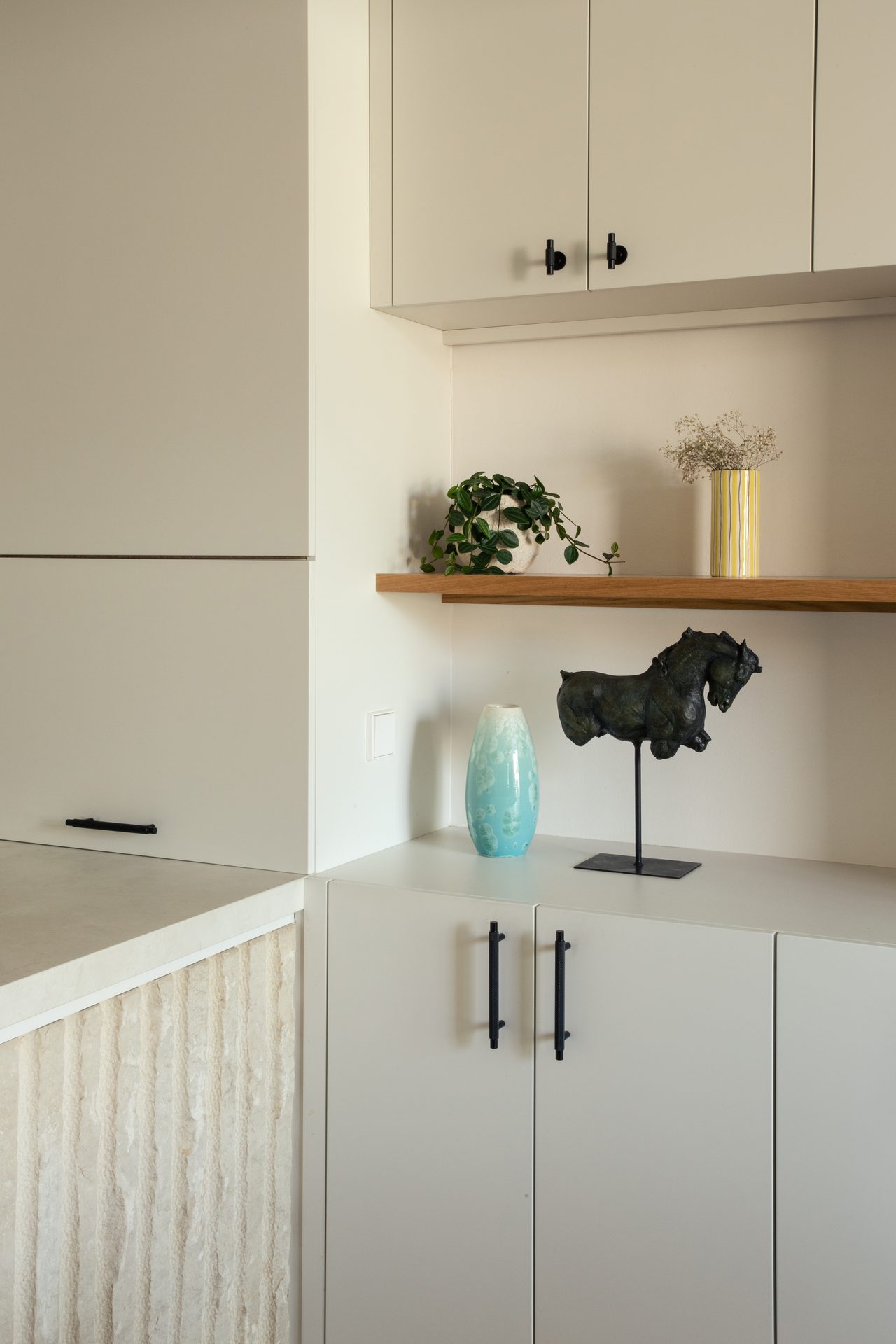 Open oak shelf and sculpture beside the fluted stone island, Apartamento Perla, Barcelona